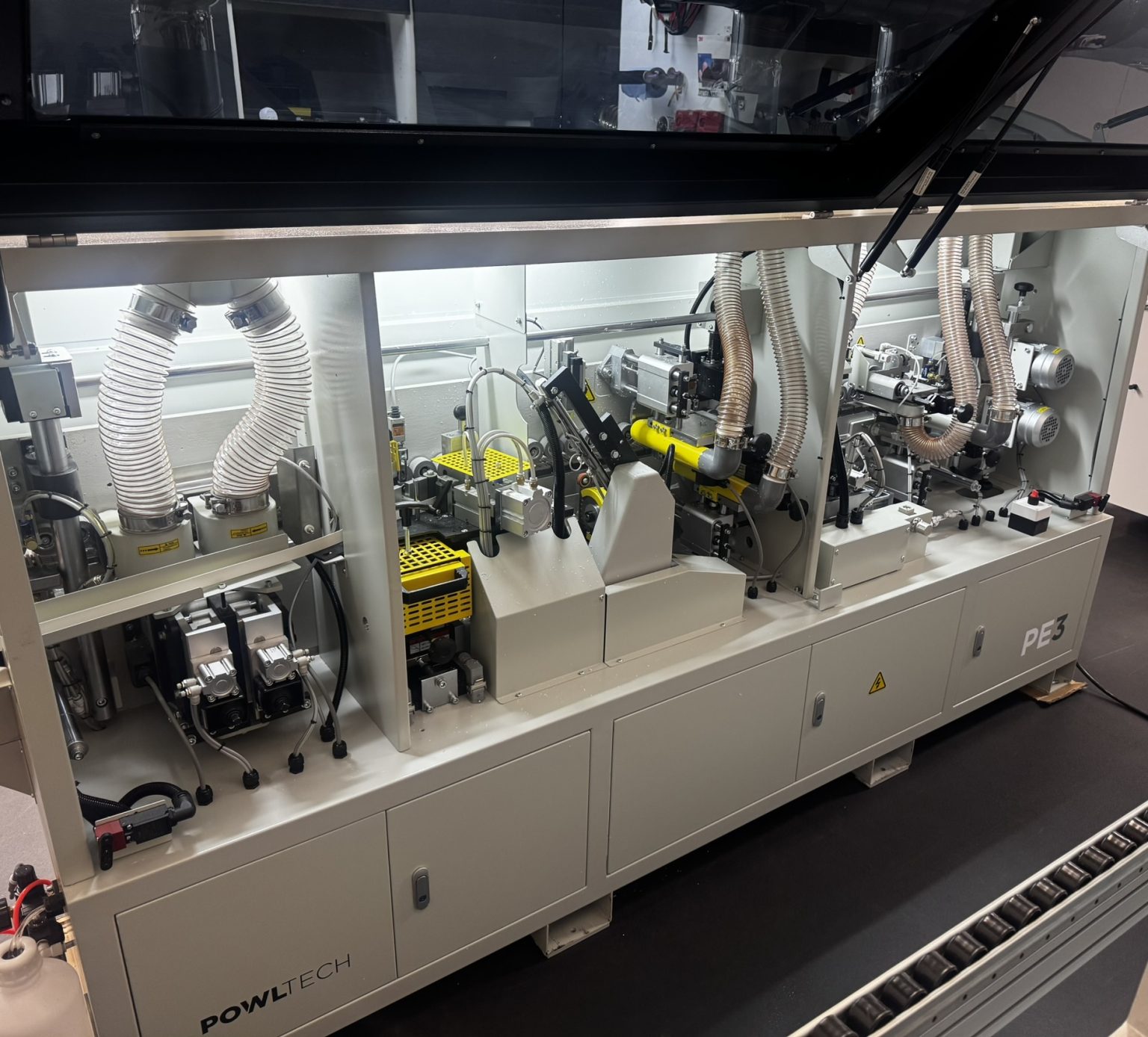 PowlTech PE3 compact edgebander internal view showing pre-milling, glue pot, end cut, fine trim and corner rounding stations in a UK workshop
